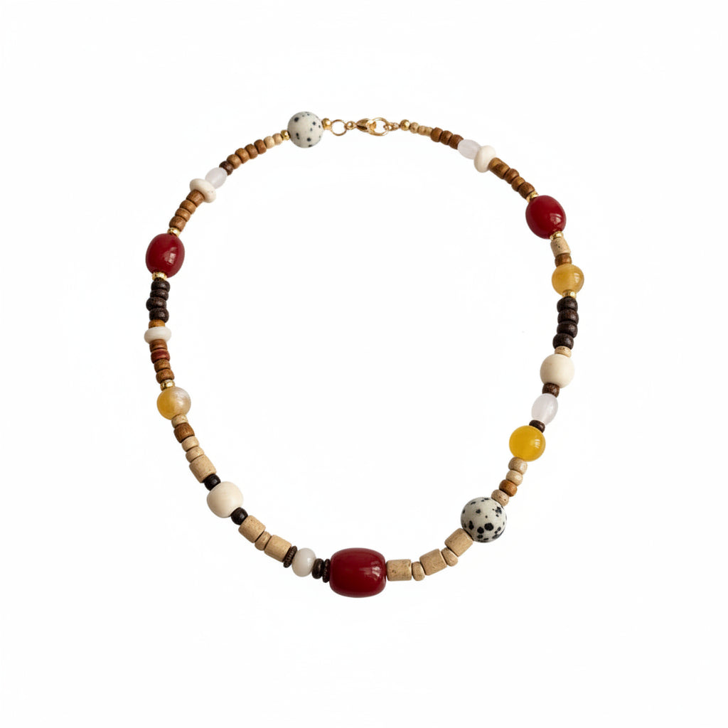 Person wearing a beige sweater with a beaded necklace