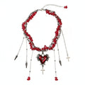 Red and silver necklace with heart and cross pendant on a dark surface