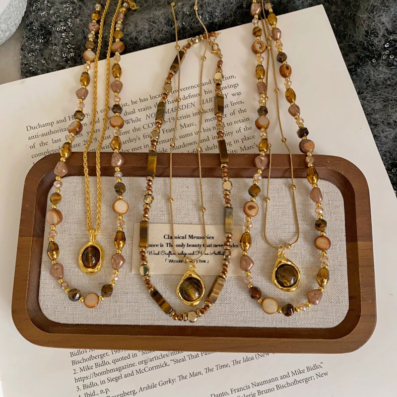Set of beaded necklaces on a wooden tray with a book underneath