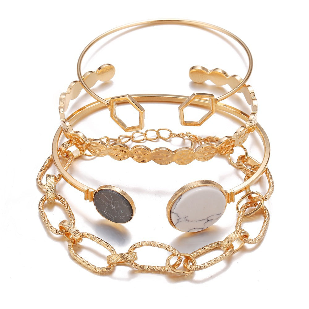Set of gold bracelets with geometric and chain designs on a white background