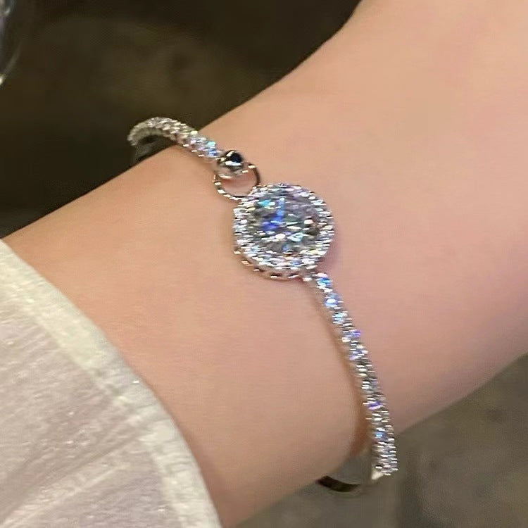 Silver bracelet with a large diamond on a wrist against a neutral background
