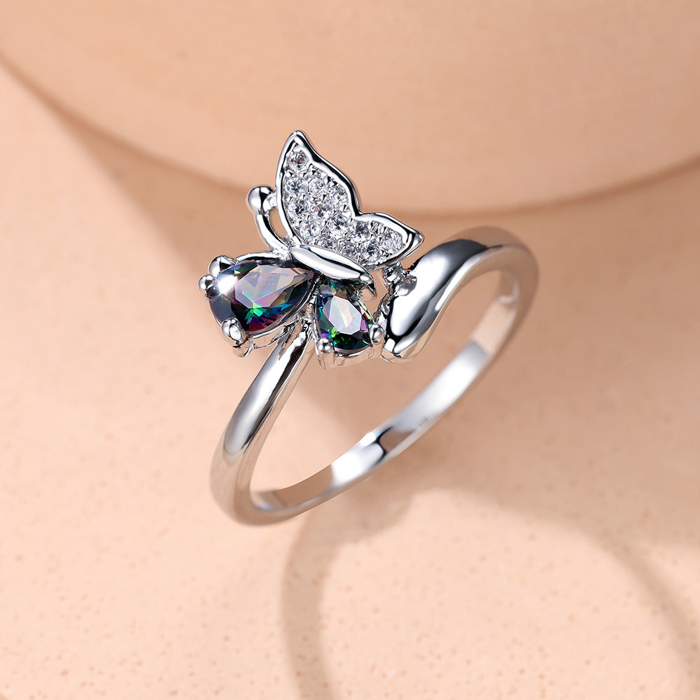 Silver butterfly ring with gemstones on a beige background