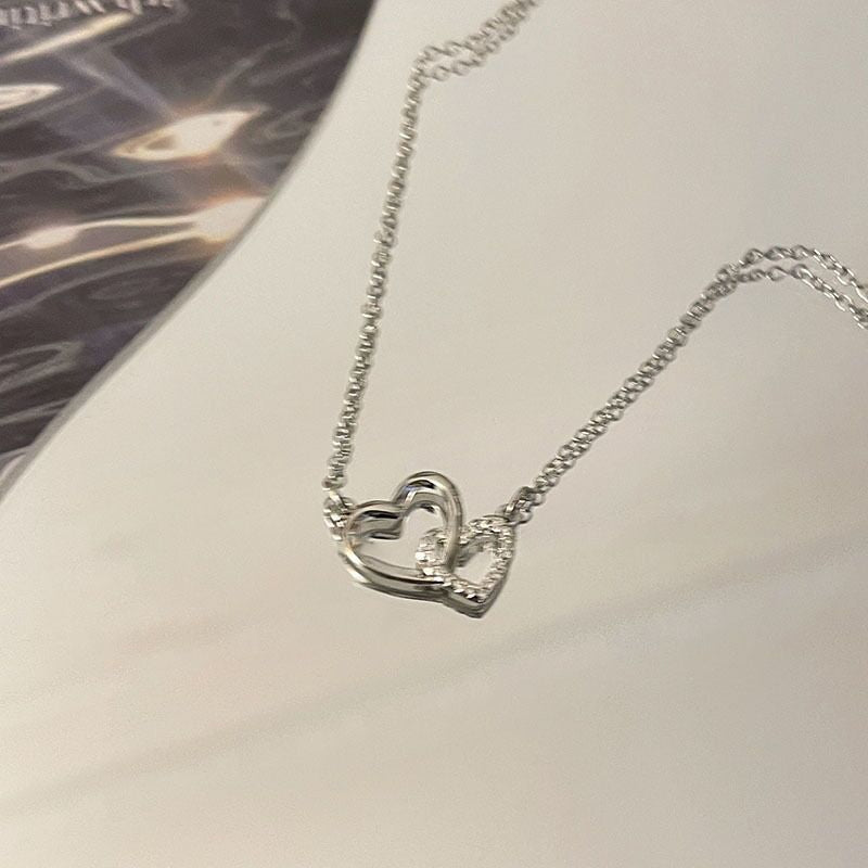 Silver heart-shaped necklace on a light gray surface