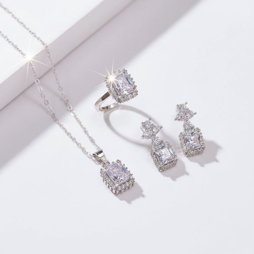 Silver jewelry set with necklace and earrings on a hand against a neutral background