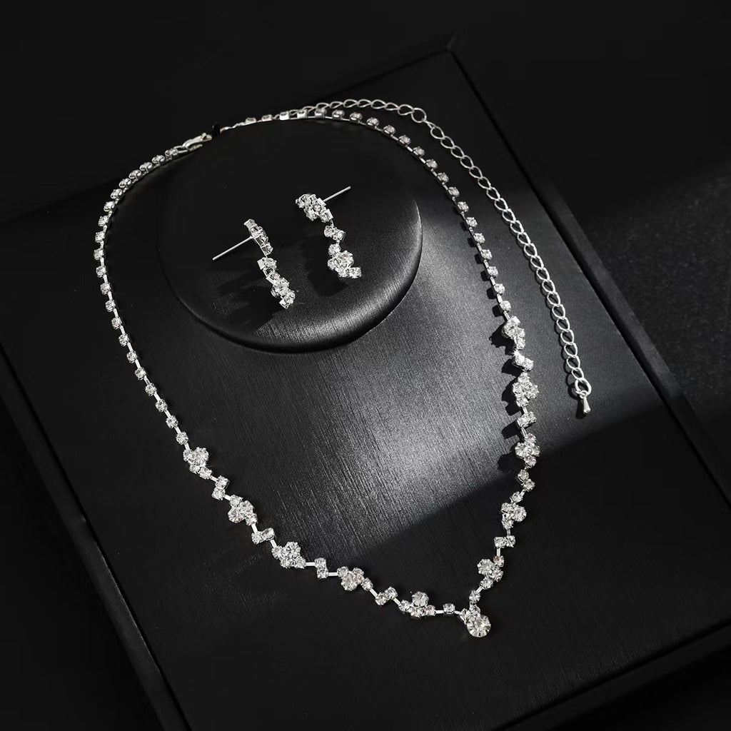 Silver necklace and earrings on a dark surface