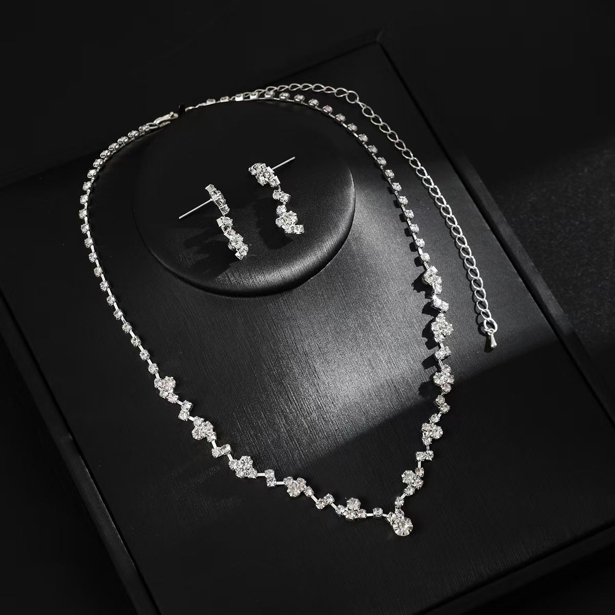 Silver necklace and earrings on a dark surface