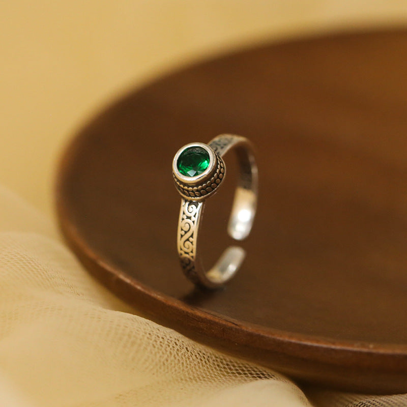 Silver ring with a green gemstone on a brown surface