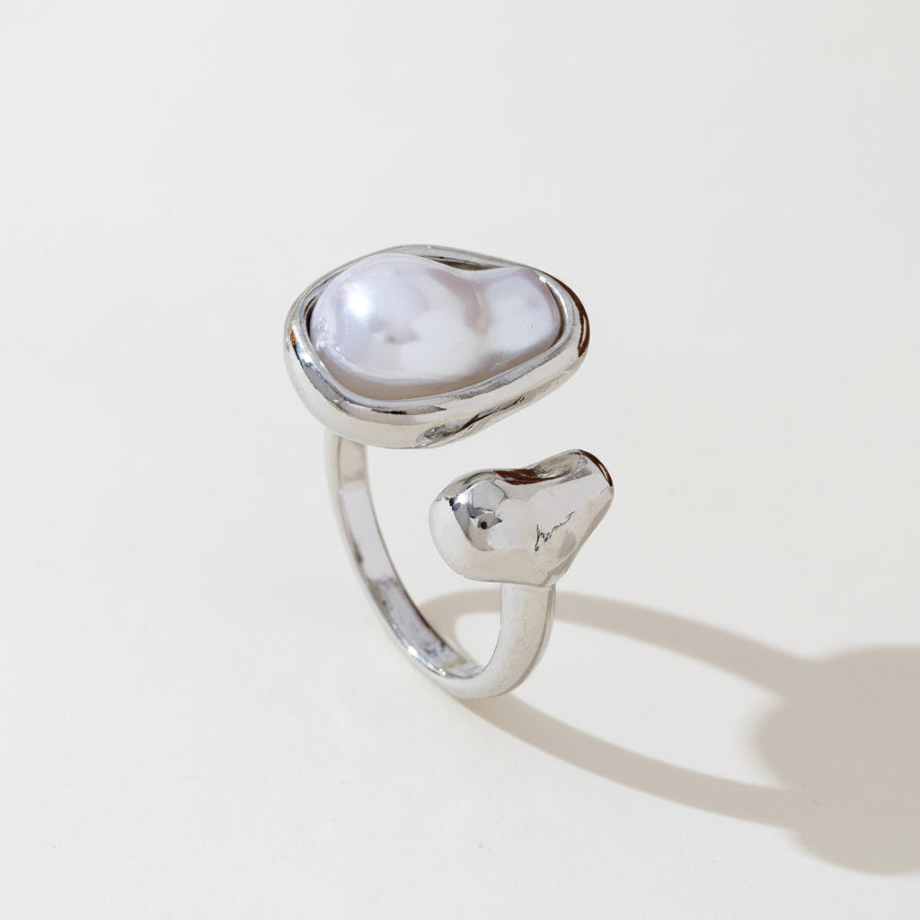 Silver ring with a large pearl-like stone on a light surface