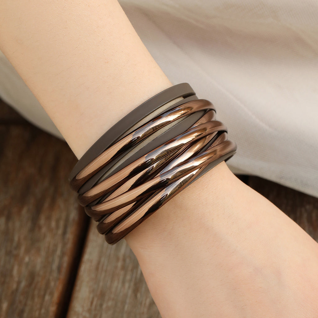 Stack of brown leather bracelets on a wrist with a neutral background