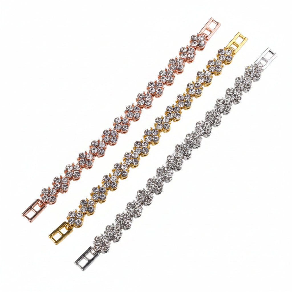 Two bracelets, one gold and one silver, on a black surface with a pink and black geometric design in the background.