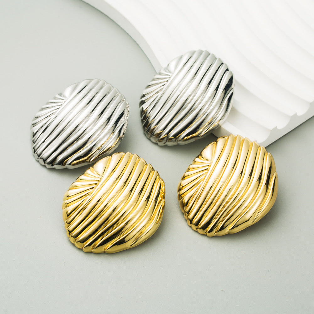 Two pairs of gold and silver earrings on a light gray background