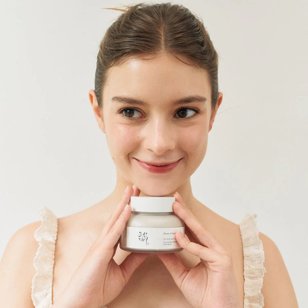 Woman holding a jar of cream against a plain background
