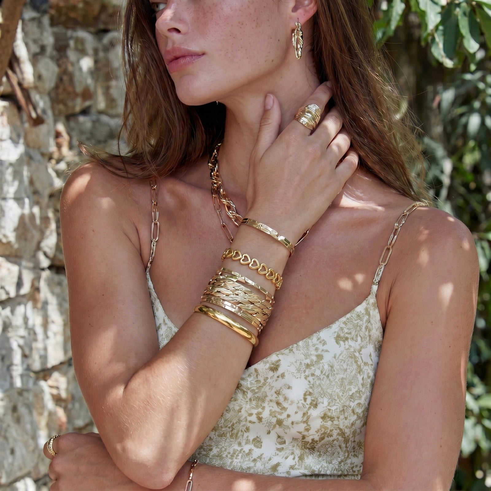 Gold 18K plated stainless steel bangle with continuous open heart links, high-polish finish, on white background.