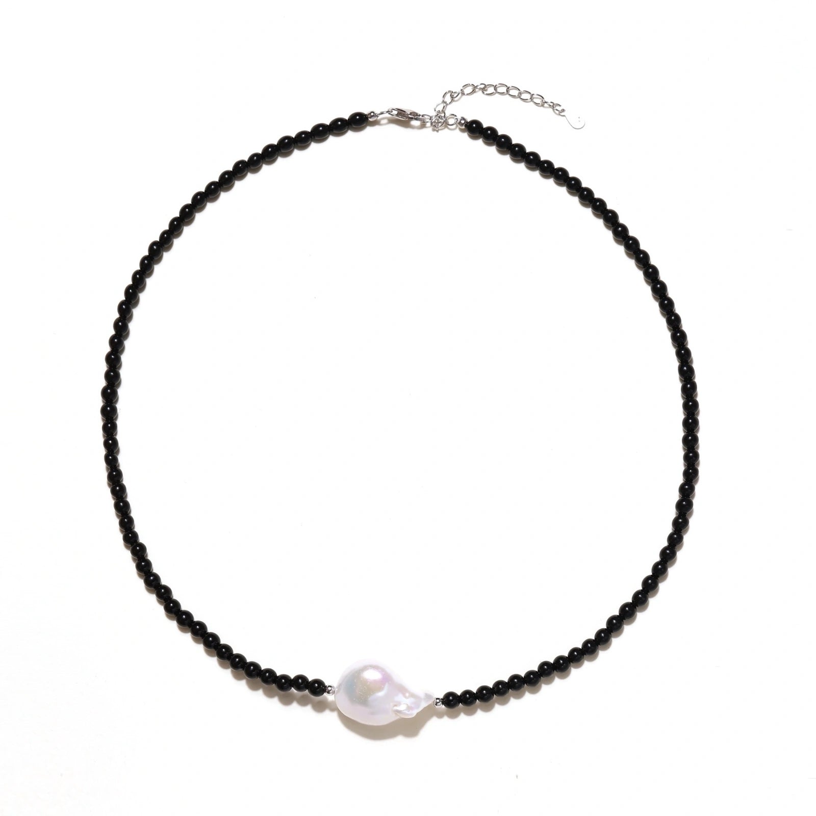 Beaded black agate necklace with iridescent baroque freshwater pearl centerpiece, close-up detail of pearl on cream background